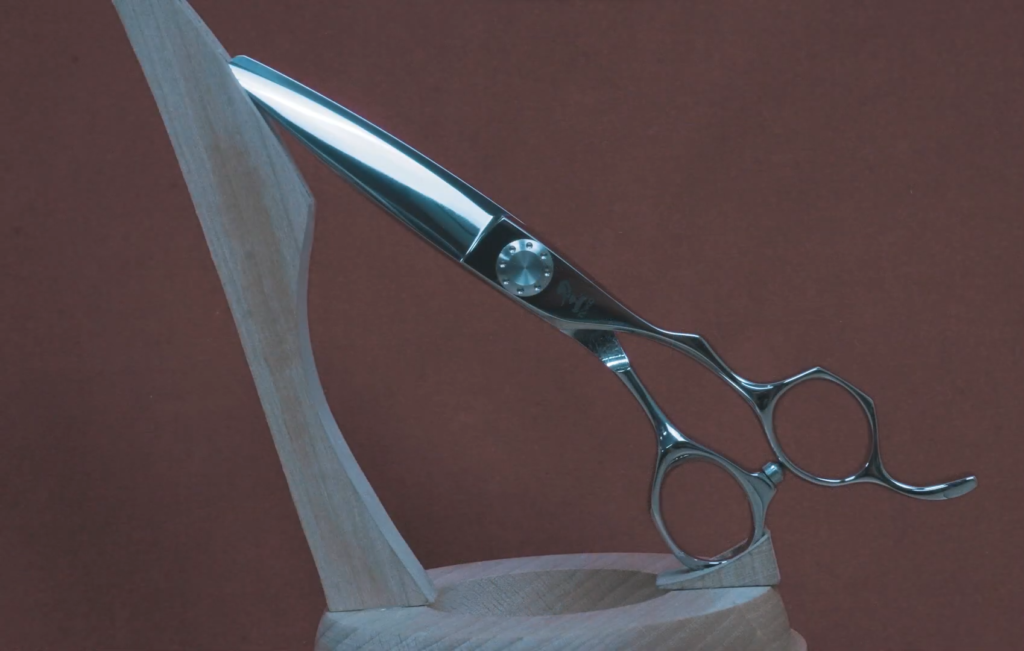 Tijeras de peluquería profesionales de acero inoxidable, exhibidas en un soporte de madera.